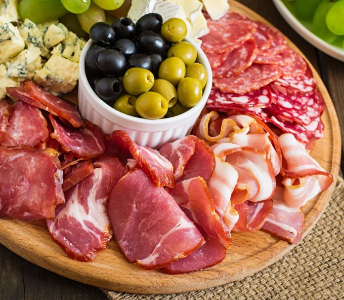 antipasto-catering-platter-with-bacon-jerky-salami-cheese-grapes-wooden-table