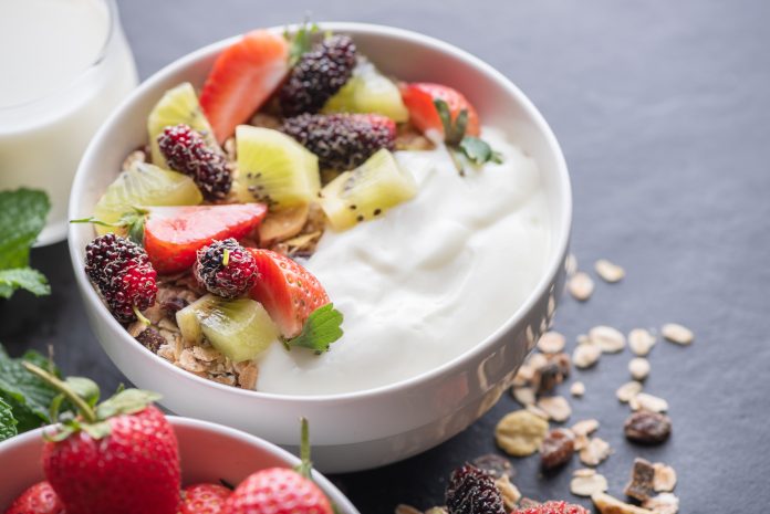 bowl of oat granola with yogurt, fresh mulberry, strawberries, k