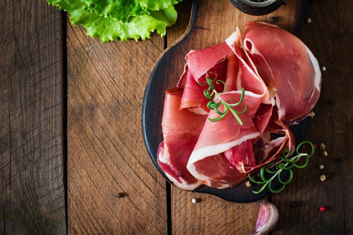 Grissini bread sticks with prosciutto on old wooden background