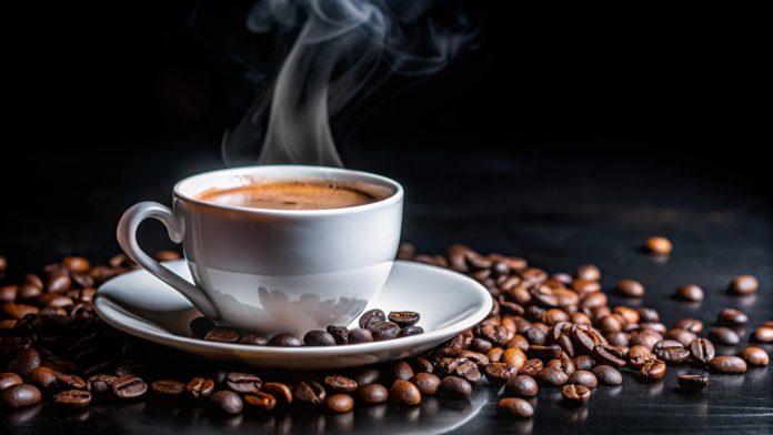 Steaming cup of coffee on a saucer with coffee beans scattered around.