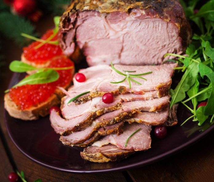 Christmas baked ham and red caviar, served on the old wooden table.