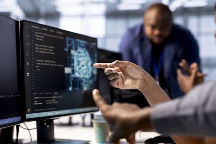 Close up of data center worker pointing finger to AI tech on PC screen