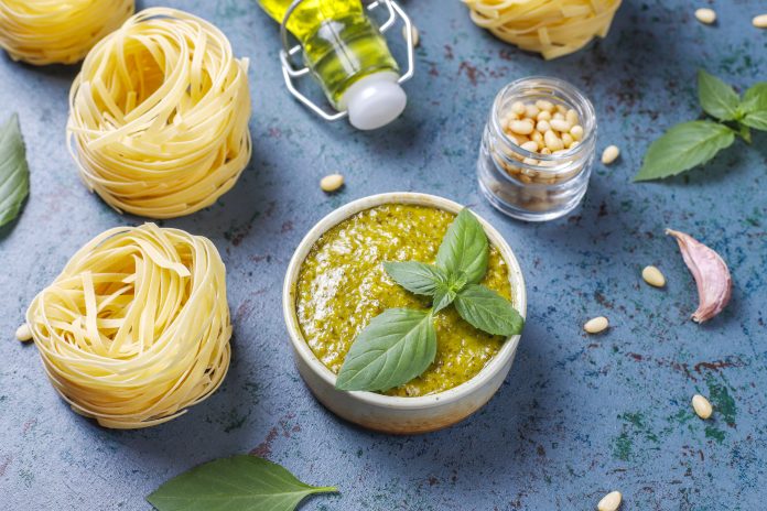 Italian basil pesto sauce with culinary ingredients for cooking.