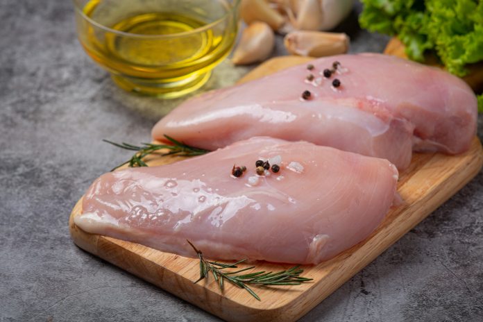 Raw chicken breast on the dark background.