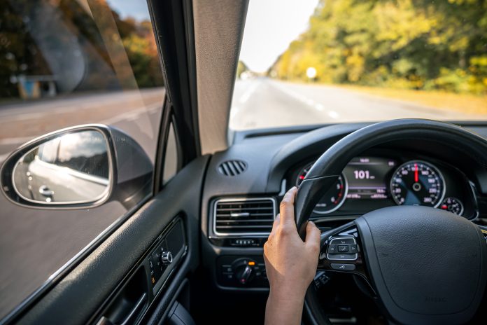 Woman driver's hands on the steering wheel inside the car.