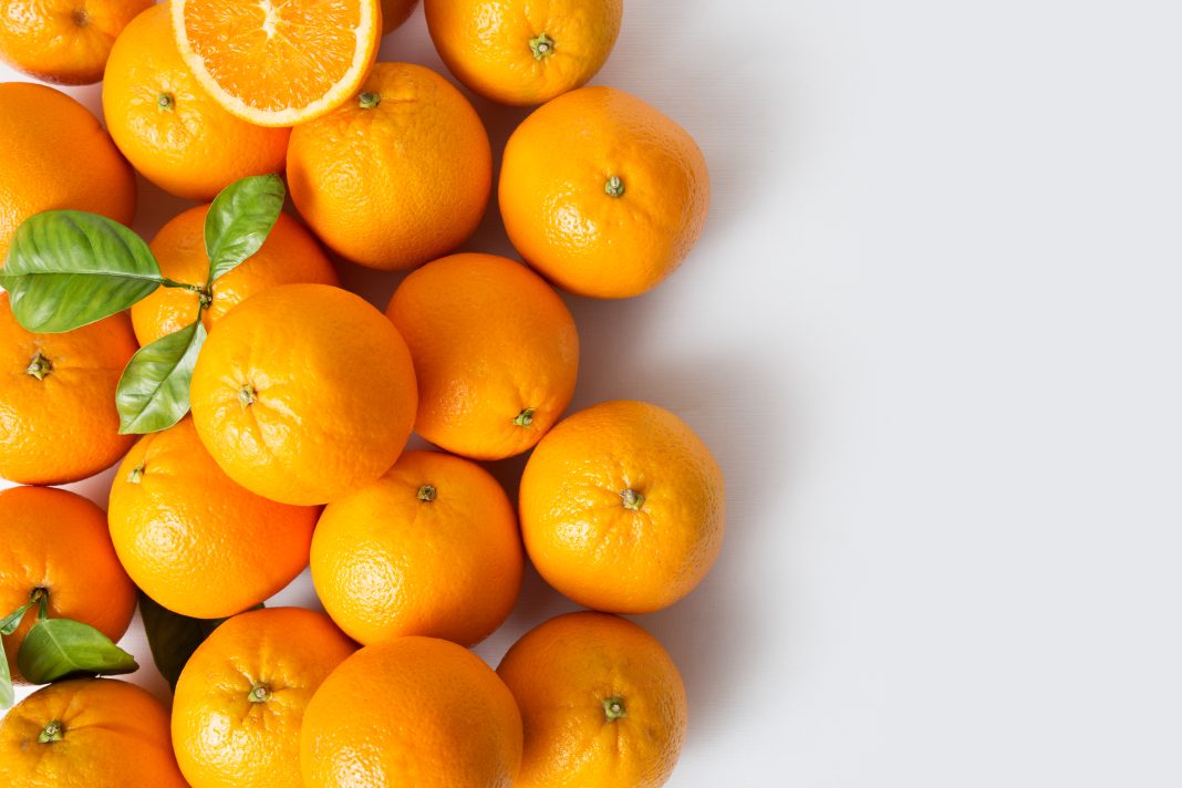 Bright juicy ripe orange fruits with leaves isolated on white