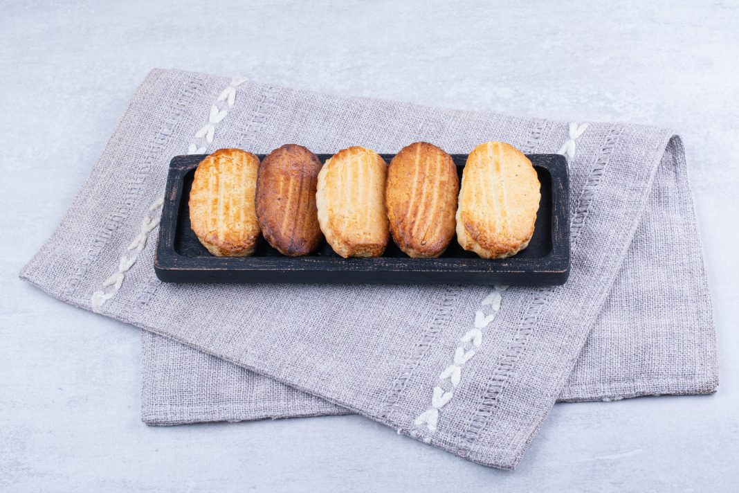 Delicious biscuits on black plate with tablecloth